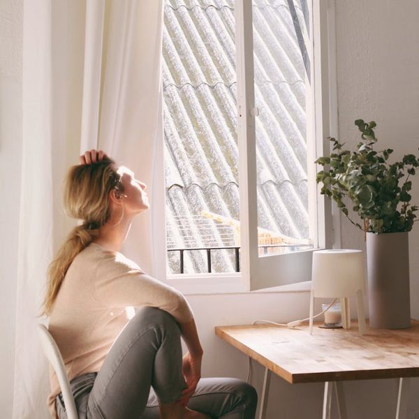 Person meditating in a bright, clean room with a look of serenity.